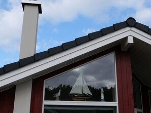 A building with a white facade, a black roof, and a window with a seagull and a sailboat model. - 4 Star Holiday Home in Grossenbrode (Grossenbrode)