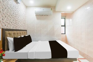 Habitación de hotel con cama, cabecera, aire acondicionado instalado en la pared y ventana.