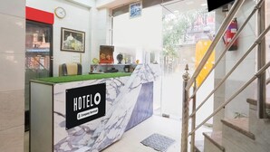 Balcão de recepção de hotel com design em mármore, um relógio e uma placa indicando que é um hotel de serviço empresarial.