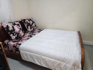 A single bed with a floral-patterned cover and a white quilt.
