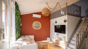 A living room with a sofa, a round table, a TV, and a staircase. - Suite Marrakech - Sauna - Jacuzzi - Swimming pool - Bicycle - ardèche (Saint-Martin-d'Ardèche)