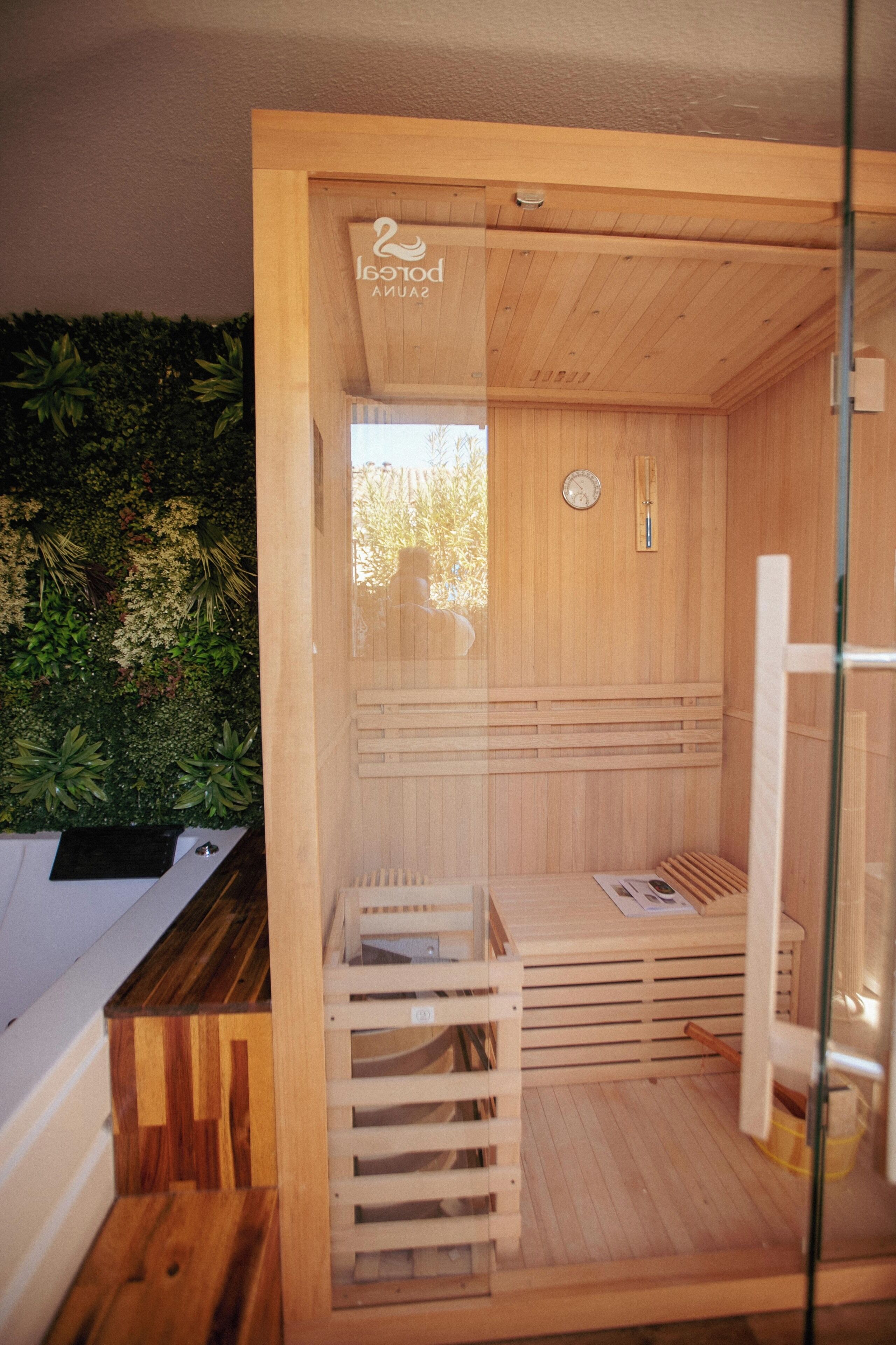 Un sauna aux murs en bois et à la porte en verre, avec une horloge et une petite fenêtre.