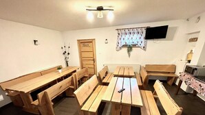A room with wooden benches and tables, a television mounted on the wall, and a radiator. - Double Room, Sauna, Masuria (Ruciane-Nida)