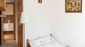 A bedroom with a single bed, a bedside lamp, a radiator, and a framed painting on the wall. - Double Room, Sauna, Masuria (Ruciane-Nida)