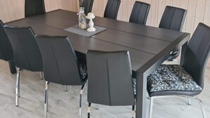Uma sala de conferência com uma mesa de madeira escura, cadeiras pretas com almofadas estampadas e um castiçal branco.