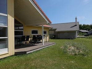 A covered outdoor seating area with chairs and tables, adjacent to a building with a tiled roof and a chimney. - 4 Star Holiday Home in Grossenbrode (Grossenbrode)
