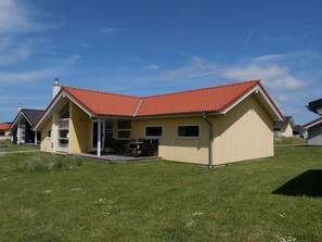 A single-story house with a red-tiled roof, a covered patio with outdoor furniture, and a grassy yard. - 4 Star Holiday Home in Grossenbrode (Grossenbrode)