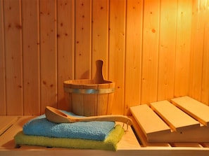 Una sauna de madera con un balde, una cuchara y una pila de toallas.
