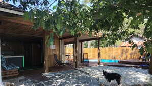 Una terraza de madera con piscina, mobiliario exterior y un porche cubierto.