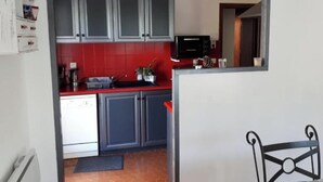 Una cocina con armarios grises, encimera roja, microondas y una lámpara colgante.