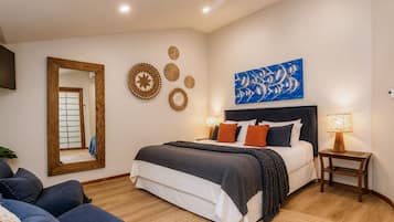 Een slaapkamer met een bed, een plafondventilator, een tv aan de muur en decoratieve wandkunst.