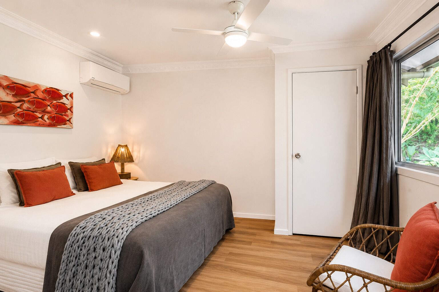 Un dormitorio con una cama, una silla, un ventilador de techo y una puerta.
