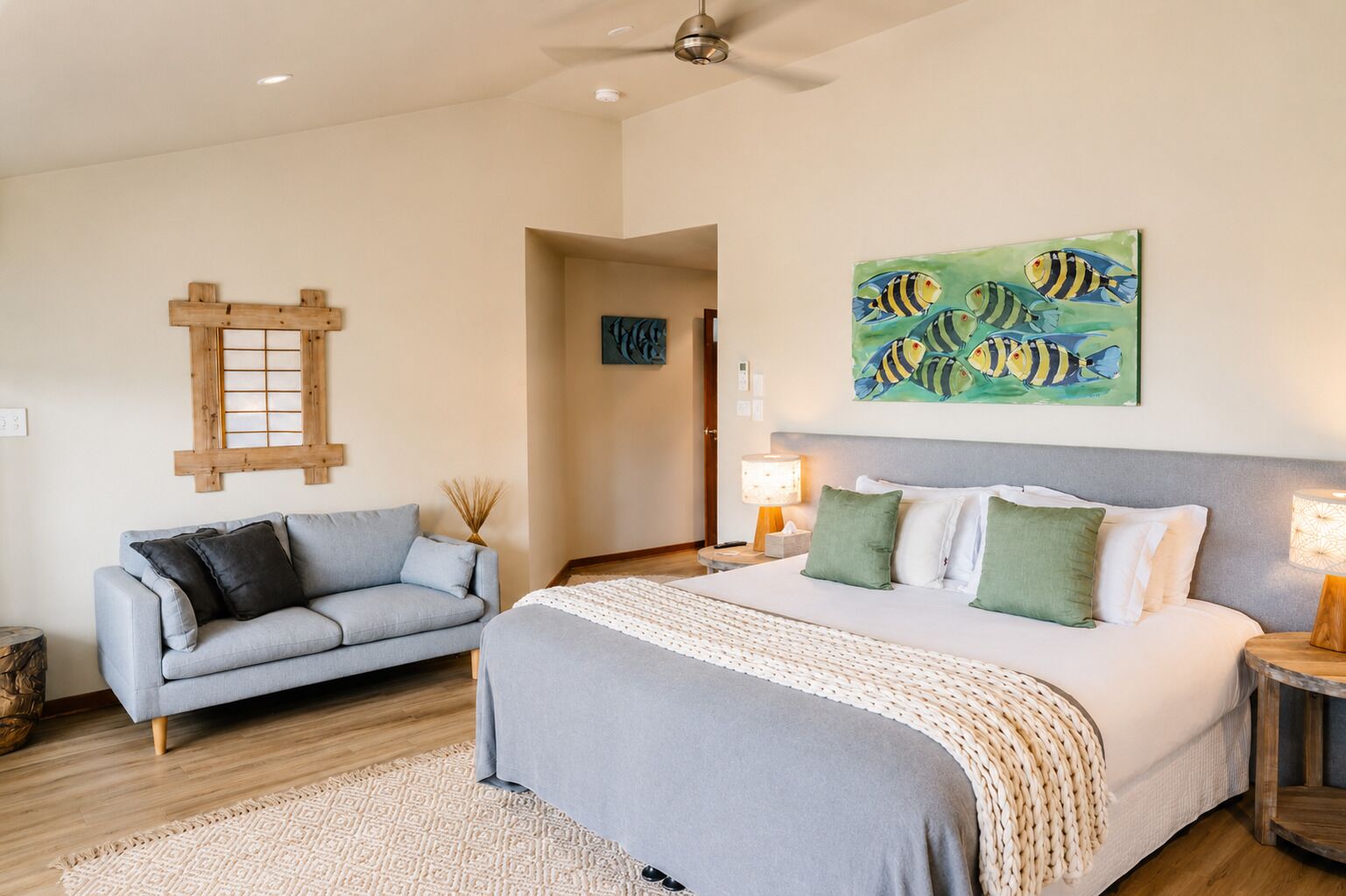 A bedroom with a bed, a sofa, a painting, and a wooden headboard.