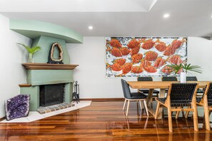 Un comedor con chimenea, una mesa con sillas y un cuadro grande con temática de peces en la pared.