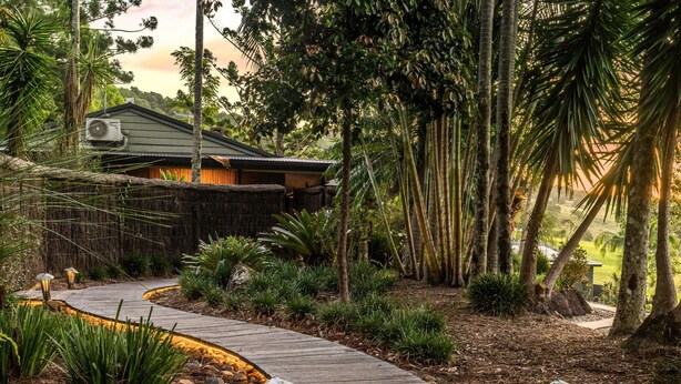 A wooden pathway leading to a house surrounded by tropical vegetation. - Cape Byron Retreat (Skinners Shoot)