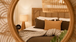 A bed with a woven headboard, a bedside lamp, and a knitted throw blanket. - Cape Byron Retreat (Skinners Shoot)