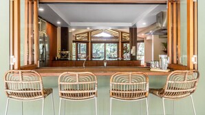 A kitchen with a large window, a stainless steel refrigerator, and wicker chairs. - Cape Byron Retreat (Skinners Shoot)