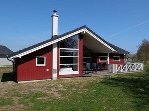 A red building with a white porch, a chimney, and a large window. - 4 Star Holiday Home in Grossenbrode (Grossenbrode)