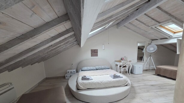 A loft bedroom with a curved bed, a desk, a chair, a small table, and a floor lamp. - DELUXE DOUBLE ROOM WITH ROUND BED IN THE CENTER OF ALBENGA UP TO 4 PEOPLE (Albenga)