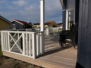 A wooden deck with a white railing, outdoor seating, and a view of surrounding houses. - 4 Star Holiday Home in Grossenbrode (Grossenbrode)