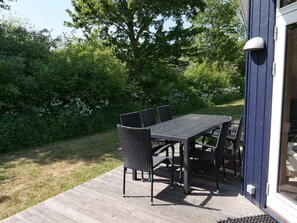 Eine Terrasse mit Tisch und Stühlen, umgeben von viel Grün.