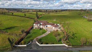 Un vaste domaine comprenant une maison principale, plusieurs dépendances et de vastes champs verdoyants.