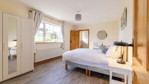 Une chambre à coucher comprenant un lit, un bureau, une chaise, une armoire, une fenêtre et une porte.