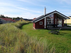 A red building with a large window and a chimney, surrounded by grass and other houses. - 4 Star Holiday Home in Grossenbrode (Grossenbrode)