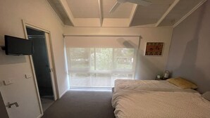 Une chambre à coucher avec un lit, un ventilateur de plafond, une porte et une fenêtre.