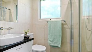 Une salle de bain avec un lavabo blanc, des toilettes et une cabine de douche en verre.