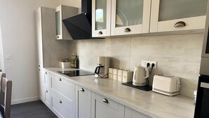 A modern kitchen with a built-in stove, coffee maker, and tea kettle. - Magnificent Family Villa Near the Ceze River (Saint-Ambroix)