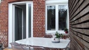 A patio with a table and chairs, a brick wall, a wooden fence, and a window. - Accommodation, terrace and secure, covered parking lot 5 minutes from Lille (Marcq-en-Barœul)