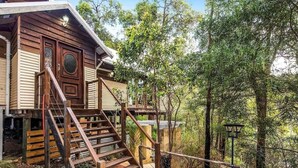 A wooden house with a staircase leading to a deck, surrounded by trees. - Bickley Tree Stay (Bickley)