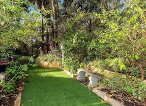 A garden pathway with a green lawn, stone benches, and various plants. - Bickley Tree Stay (Bickley)