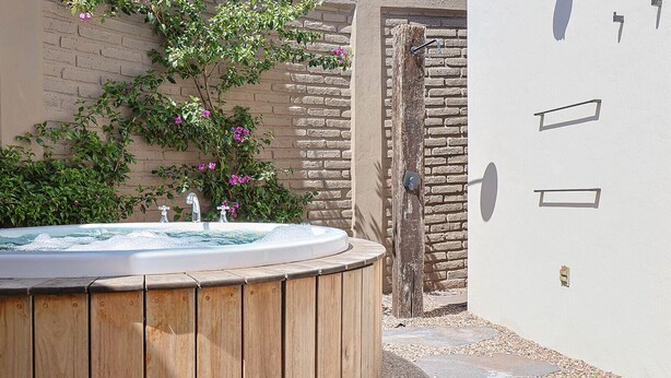 A wooden hot tub with a brick wall and a door in the background. - Private Hot Tub - 2BR in Nueva Escondida (San Miguel de Allende)