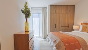 A hotel room with a bed, a wooden wardrobe, a desk with a vase, and a window with curtains. - Private Hot Tub - 2BR in Nueva Escondida (San Miguel de Allende)