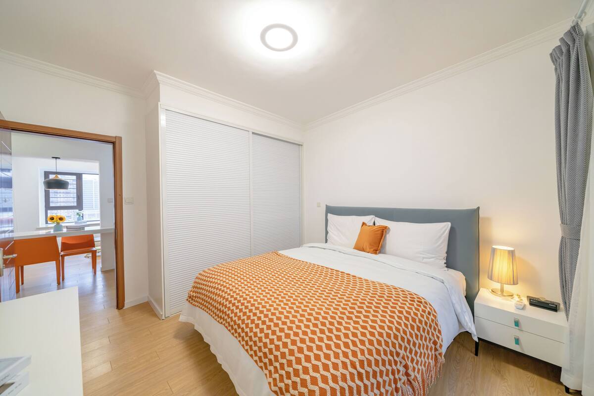 Un dormitorio con cama, mesita de noche y lámpara.