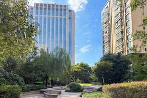A tall building with a modern design, surrounded by lush greenery and a well-maintained garden. - Tyms High Serviced Residence Shanghai Caohejing (Shanghai)