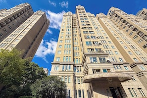 Un edificio de gran altura con varios pisos, ventanas amplias y una entrada destacada con un balcón curvo.