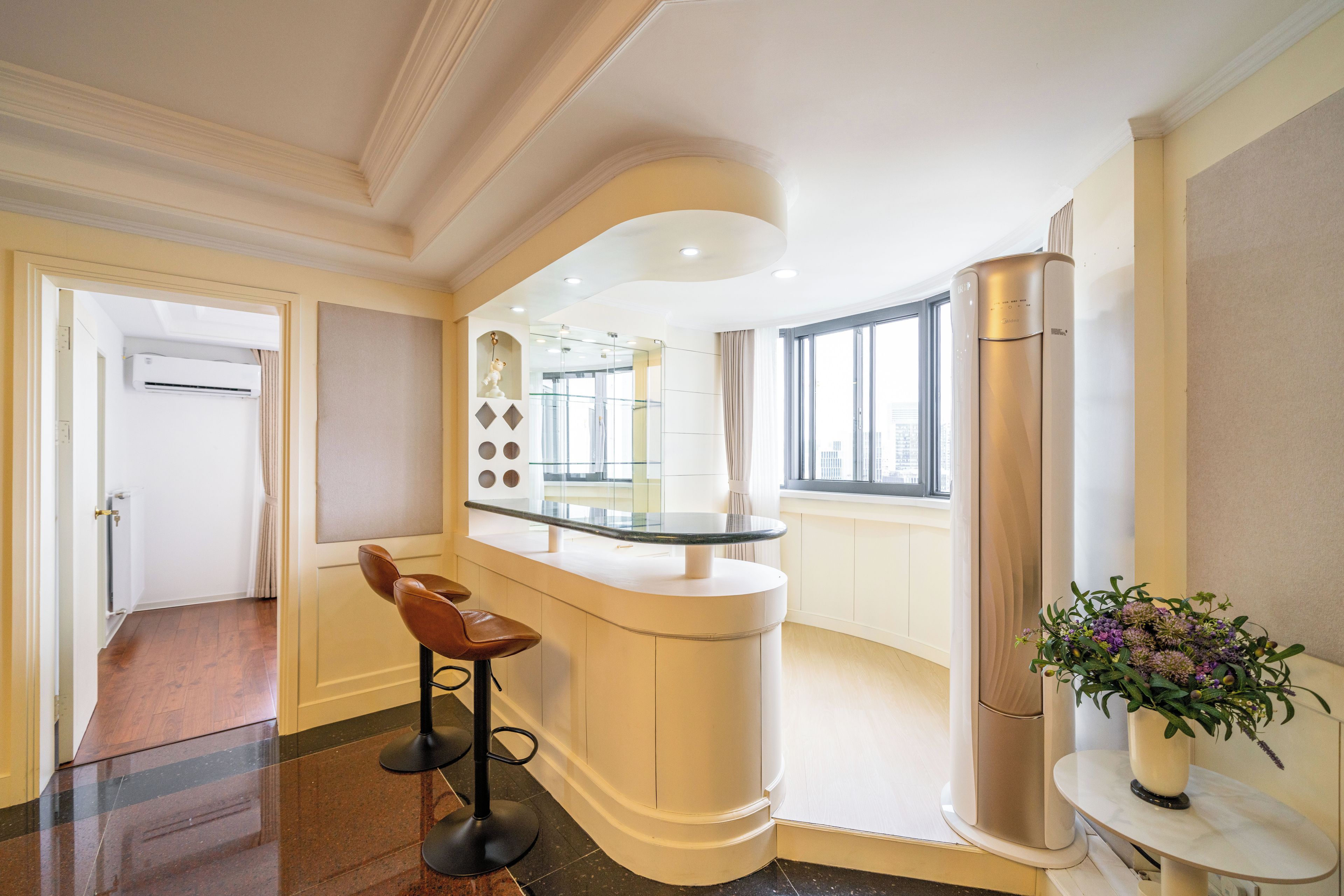 Un intérieur moderne avec un bar aux lignes courbes, un espace salon et une grande fenêtre offrant une vue panoramique.