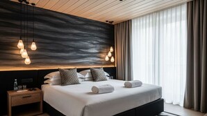Una habitación de hotel moderna con una cama grande, mesitas de noche, un cabecero con iluminación ambiental y vistas al exterior.