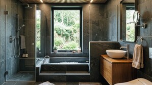 Un baño moderno con un ventanal grande, una bañera, un lavamanos y una ducha.
