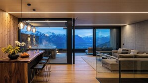 Un interior moderno con una barra de madera, zona de estar y un amplio ventanal con vistas a la montaña.