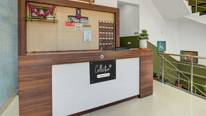 Una reception con un cartello che indica una postazione caffè, un segnale di parcheggio e un orologio a parete.