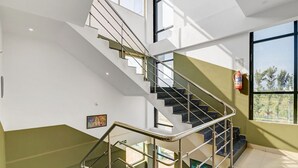 Una moderna scala con ringhiere in vetro, un estintore e opere d'arte alle pareti.