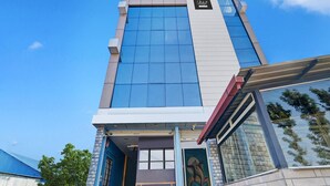Un edificio moderno con facciata in vetro, un ingresso ben visibile e una segnaletica che indica un albergo.