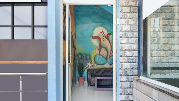 Un corridoio interno con una porta blu, un muro in pietra e un murale colorato.