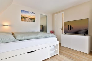 A bedroom with a bed, a television, a mirror, and artwork on the wall. - Beach thistle - Westerland (Westerland)