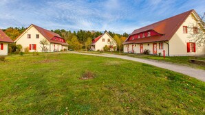 Eine Reihe von Häusern mit roten Dächern und weißen Wänden, ein klarer Himmel und eine Rasenfläche im Vordergrund.