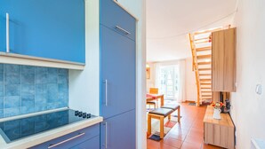 Eine kleine Küche mit blauen Schränken, einem Gasherd und einem Essbereich mit Holztisch und Stühlen.